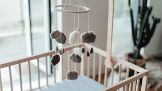 photo of a baby mobile with soft cloud shapes and rain drops hanging above an empty crib
