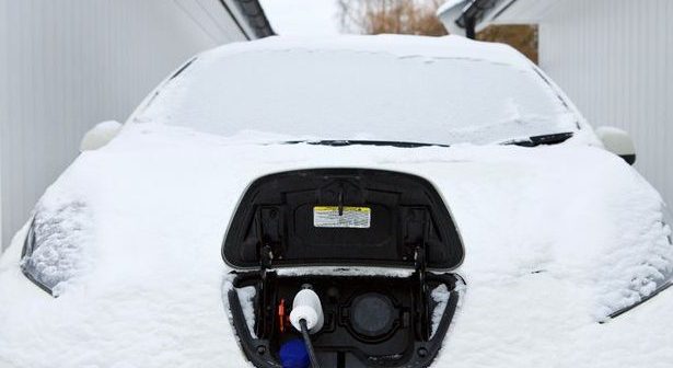 An electric car being charged on a snowy winter day