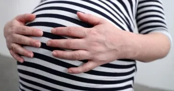 A pregnant woman holding her stomach.